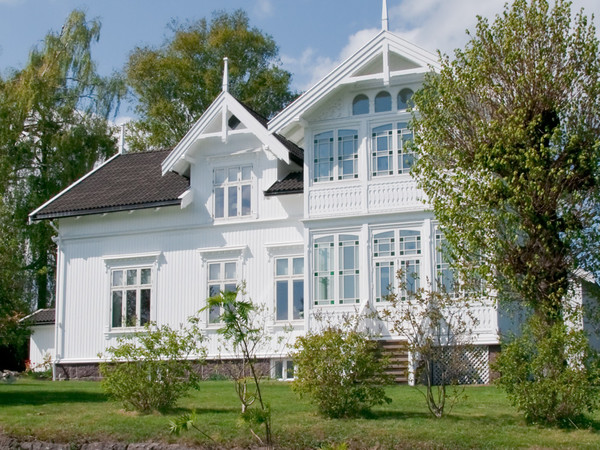 Klassisk hvit villa med utvendig Rustikk kledning og stor idyllisk hage
